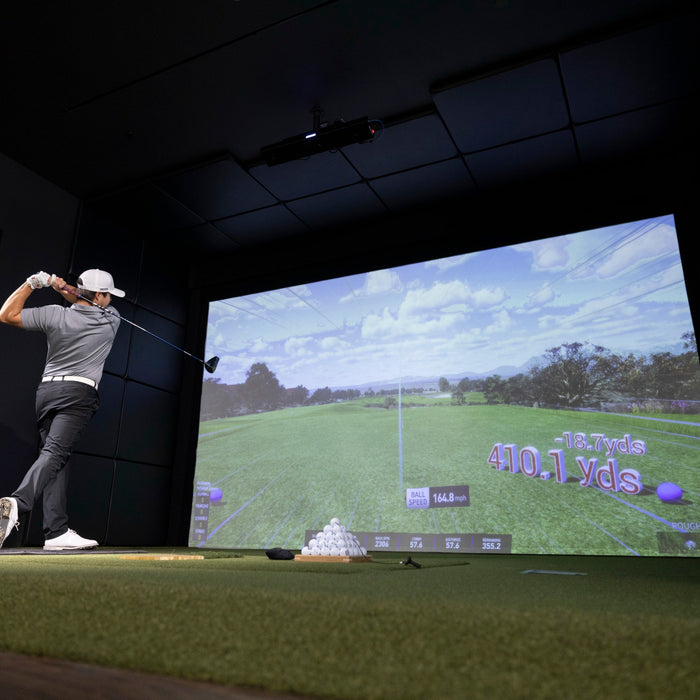 Golfer finishing a drive in a golf simulator bay