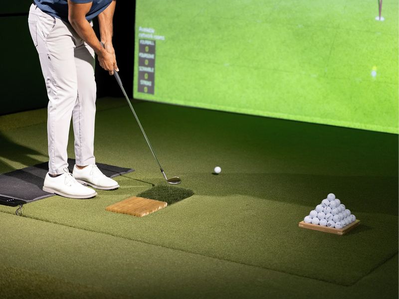 Golfer hitting off the Uneekor EYE XO2 Trouble Mat in a golf simulator setup