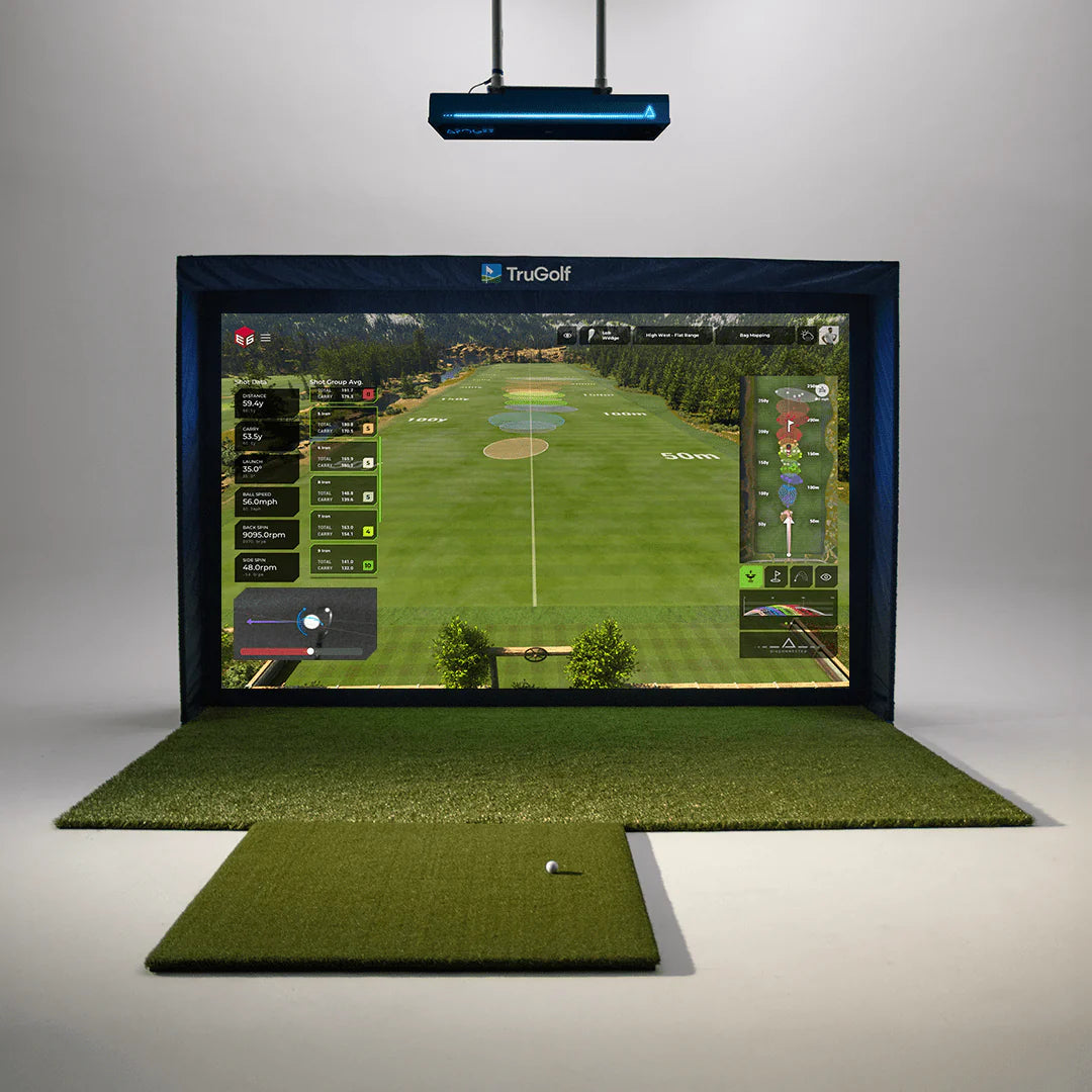 Indoor golf simulator setup with the TruGolf APOGEE launch monitor mounted on the ceiling above an impact screen showing a golf course, with hitting mats and a golf ball on the floor below