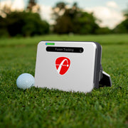 Mevo+ golf tracking device on grass with a golf ball nearby
