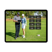 Two people on a golf course with a tablet displaying golf analytics.