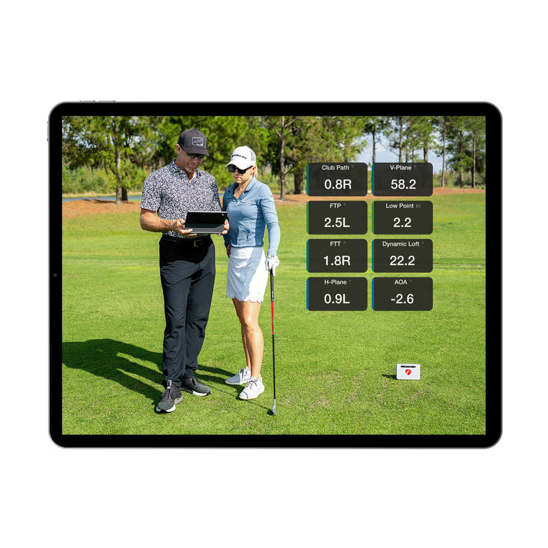 Two people on a golf course with a tablet displaying golf analytics.