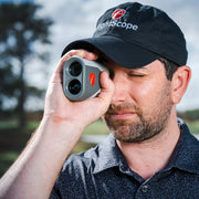 Man wearing a black cap with 'FlightScope' logo, holding a FlightScope i4 Rangefinder outdoors.
