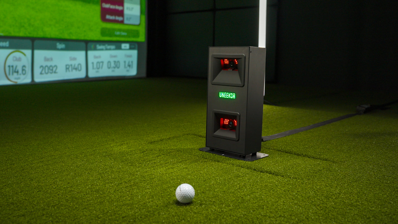 Uneekor EYE MINI LITE launch monitor on turf with a golf ball and shot data on screen