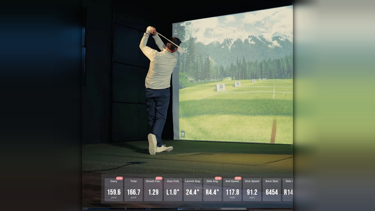 Golfer swinging in a Uneekor Eye XR golf simulator with mountain course on screen and live shot data displayed