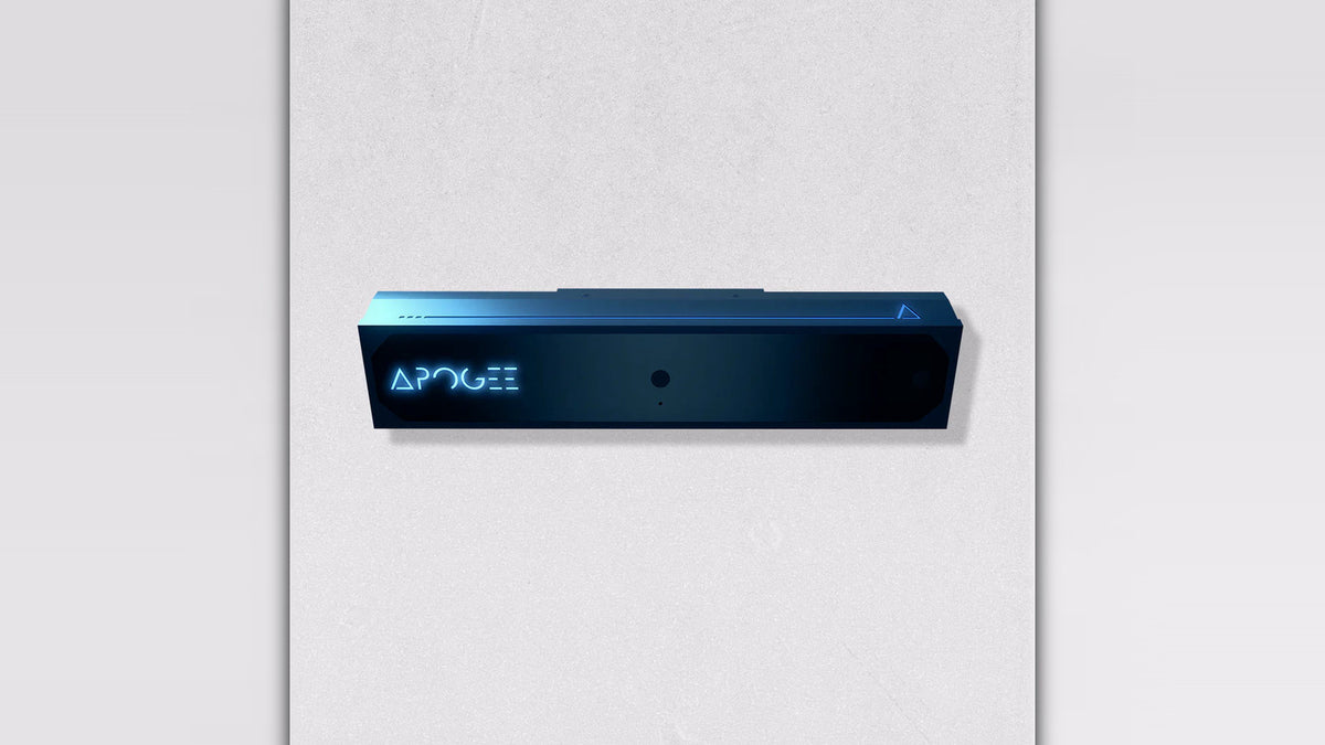 Front view of the TruGolf APOGEE launch monitor unit, a dark rectangular device with APOGEE branding and a sensor lens, on a light gray background