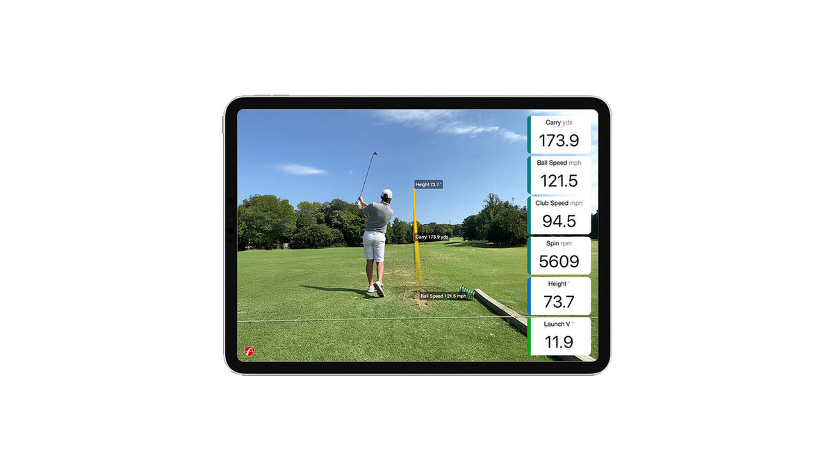 Tablet showing a golfer finishing his swing on a driving range with a yellow shot trace overlay and readouts for carry, ball speed, club speed, spin, height and launch angle from the FlightScope Mevo Gen 2